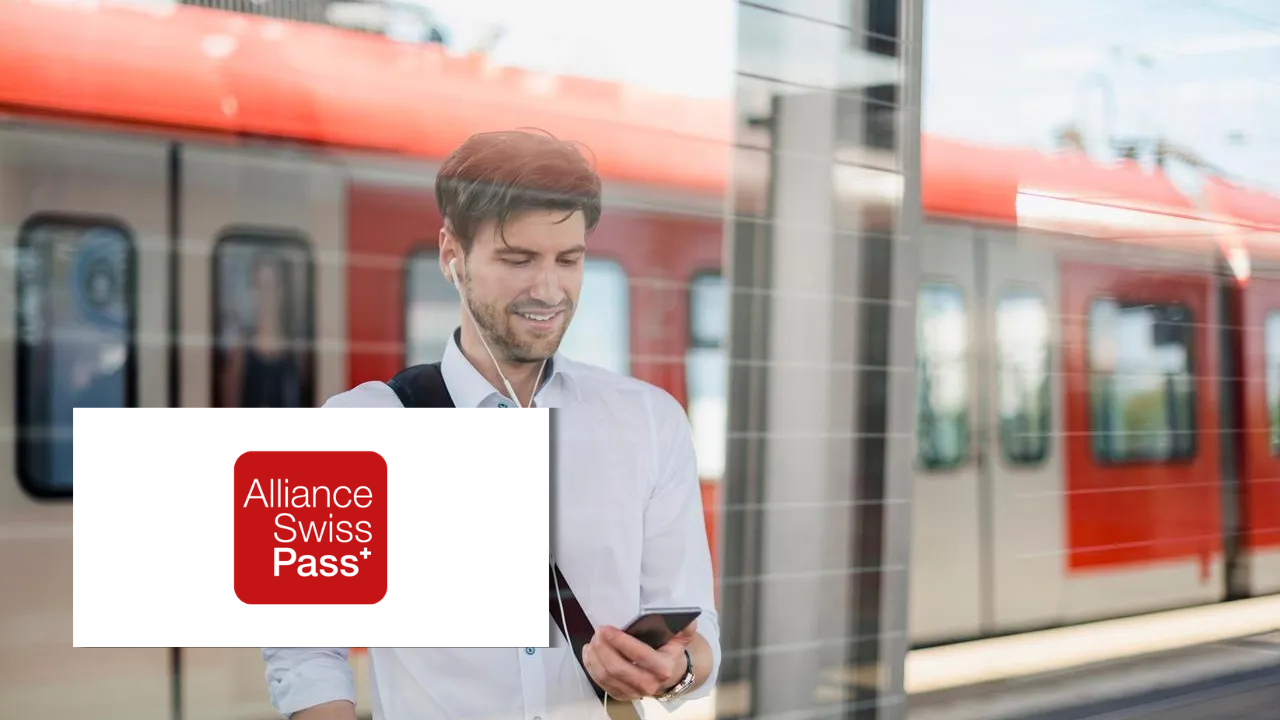 A man with earphones checking his phone on a train platform, with a train passing behind him, next to the Alliance Swiss Pass+ logo.