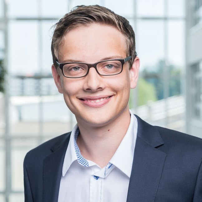 A smiling young man in glassess portrait in a light office setting