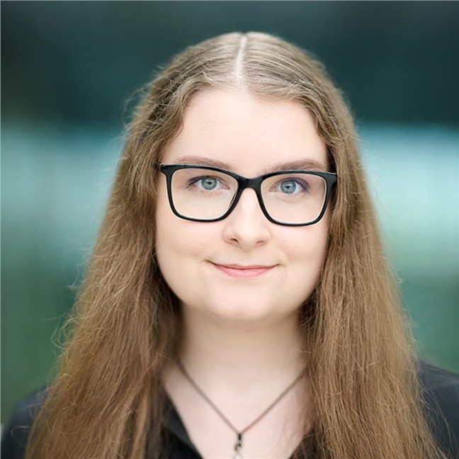 A smiling woman in black glasses portrait in an office setting