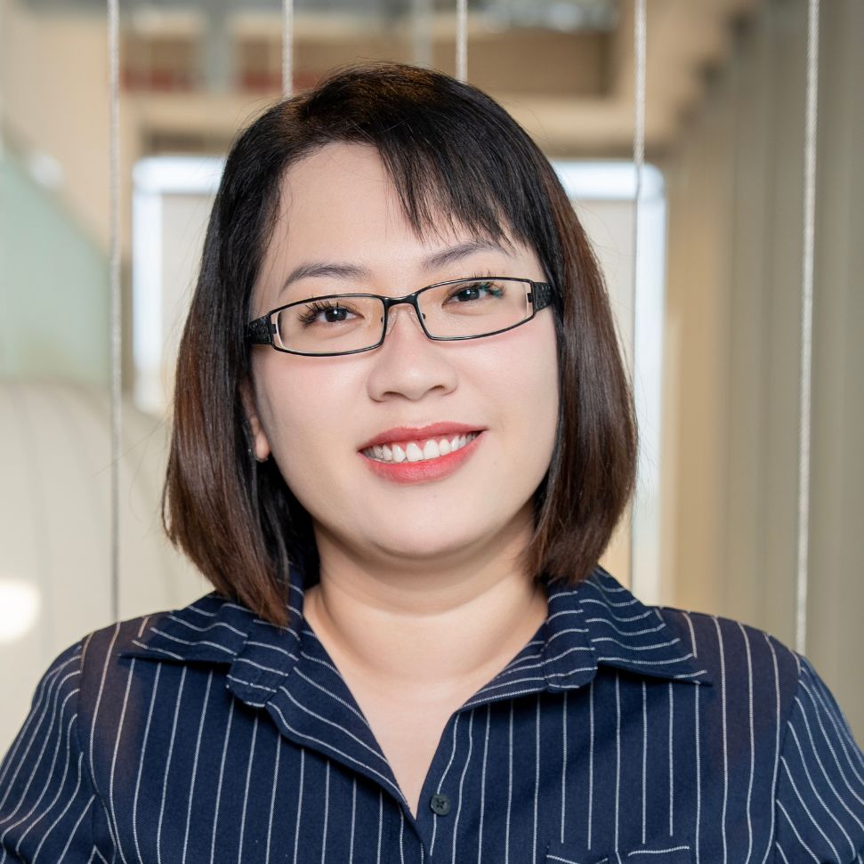 Portrait of a smiling woman wearing glasses in a modern office environment.
