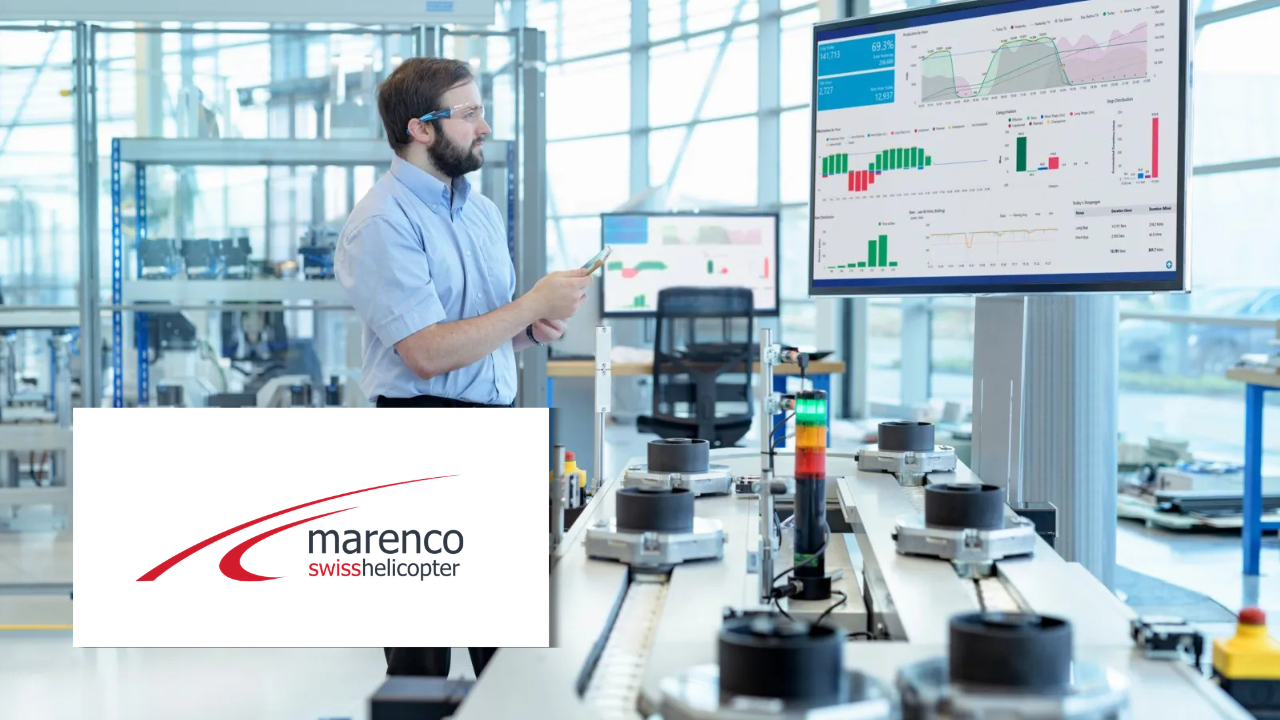 An engineer using smart glasses to view a production dashboard on a screen in a manufacturing facility, next to the Marenco Swiss Helicopter logo.