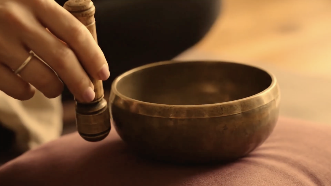 A hand performing a meditation ceremony of 'singing bowls'