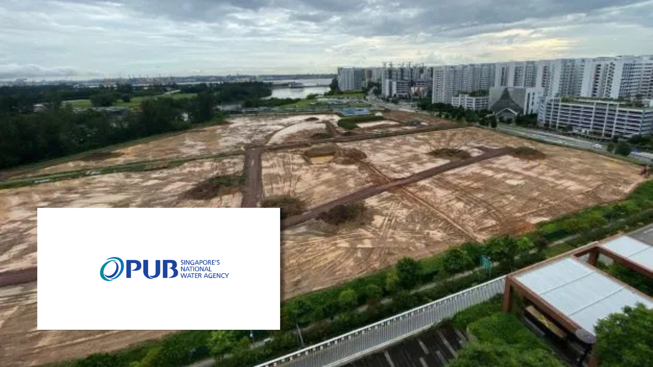 Aerial view of a cleared construction site bordered by a river and high-rise buildings, next to the PUB Singapore's National Water Agency logo.