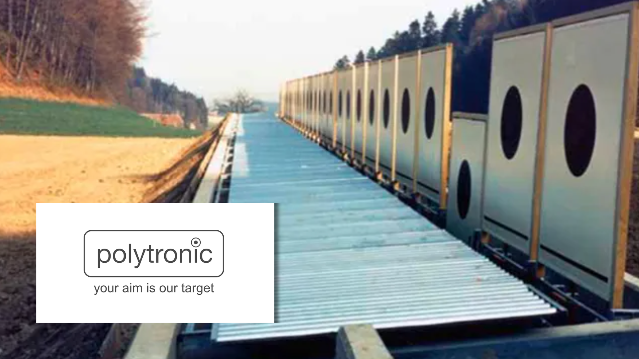 A row of large sound barrier panels installed along a roadway in a rural landscape, next to the Polytronic "your aim is our target" logo.