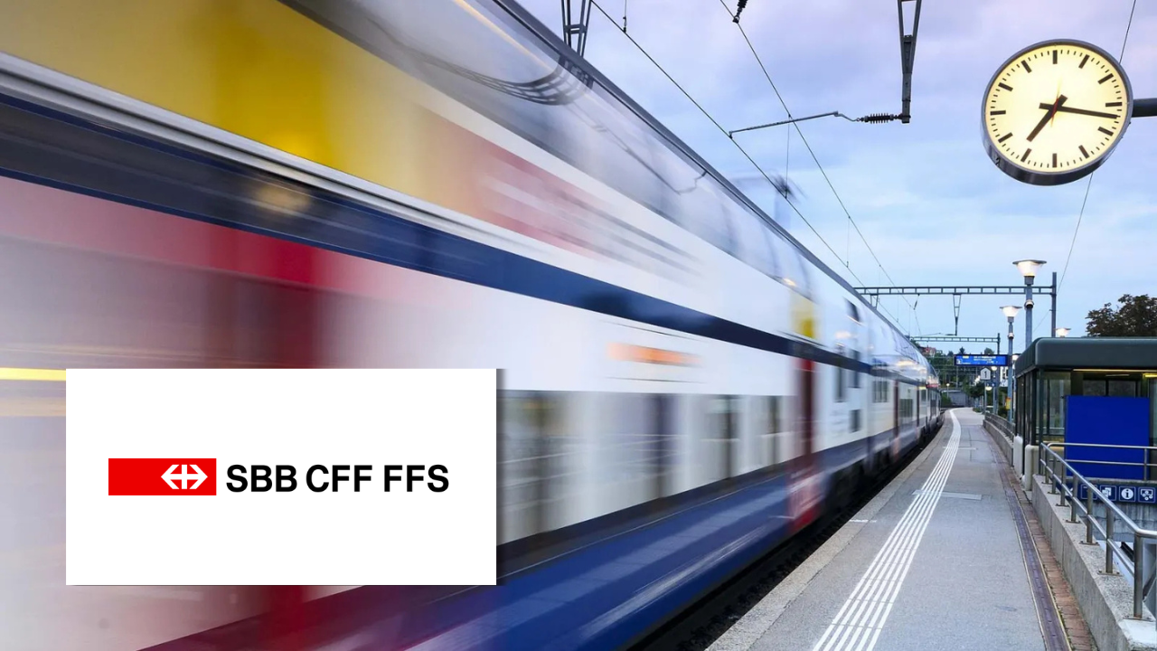 A train in motion passing a station platform beneath the iconic Swiss railway clock, next to the SBB CFF FFS logo.