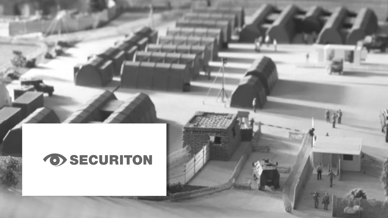 A black-and-white scale model of a military base or checkpoint with tents, barriers, and guarded entry points, next to the Securiton logo.