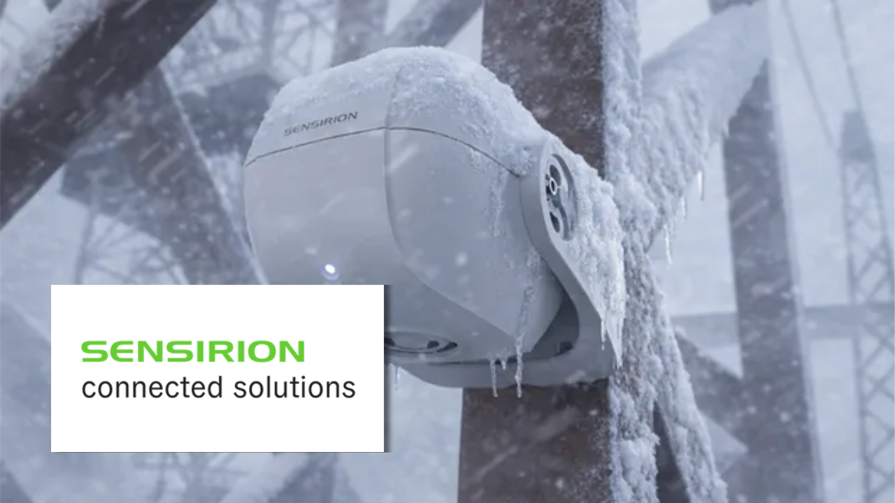 A snow-covered Sensirion sensor device mounted on an outdoor pole, coated in ice and snow during winter weather, with the Sensirion connected solutions logo overlaid.