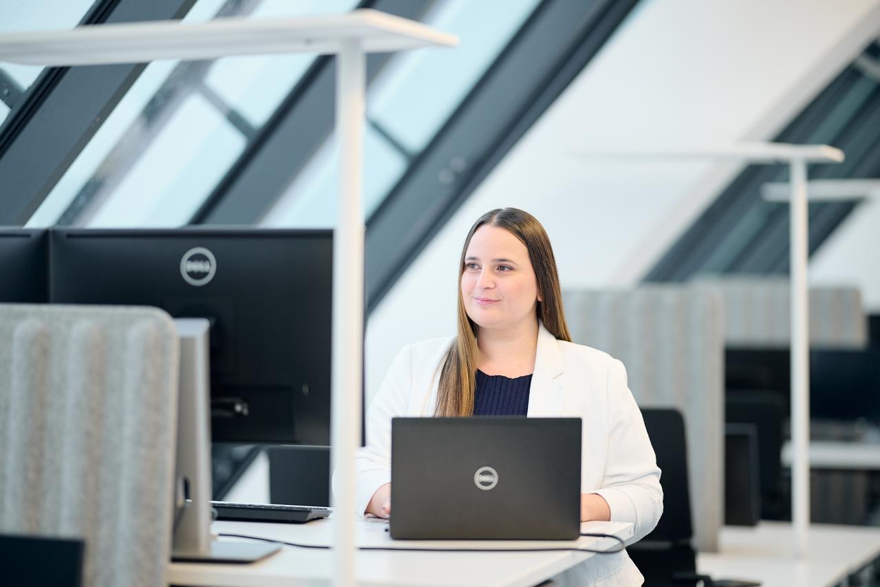 A smiling woman portrait in the light office setting at a standing desk