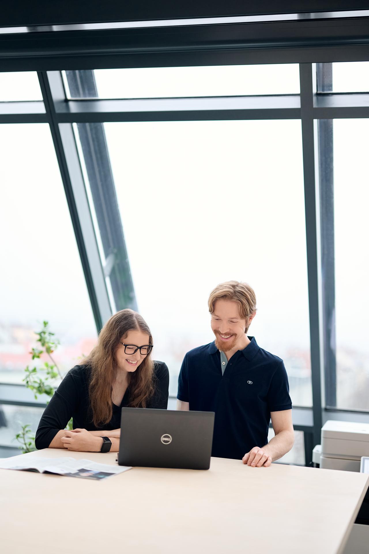 Two colleagues in a modern office in front of the full height window