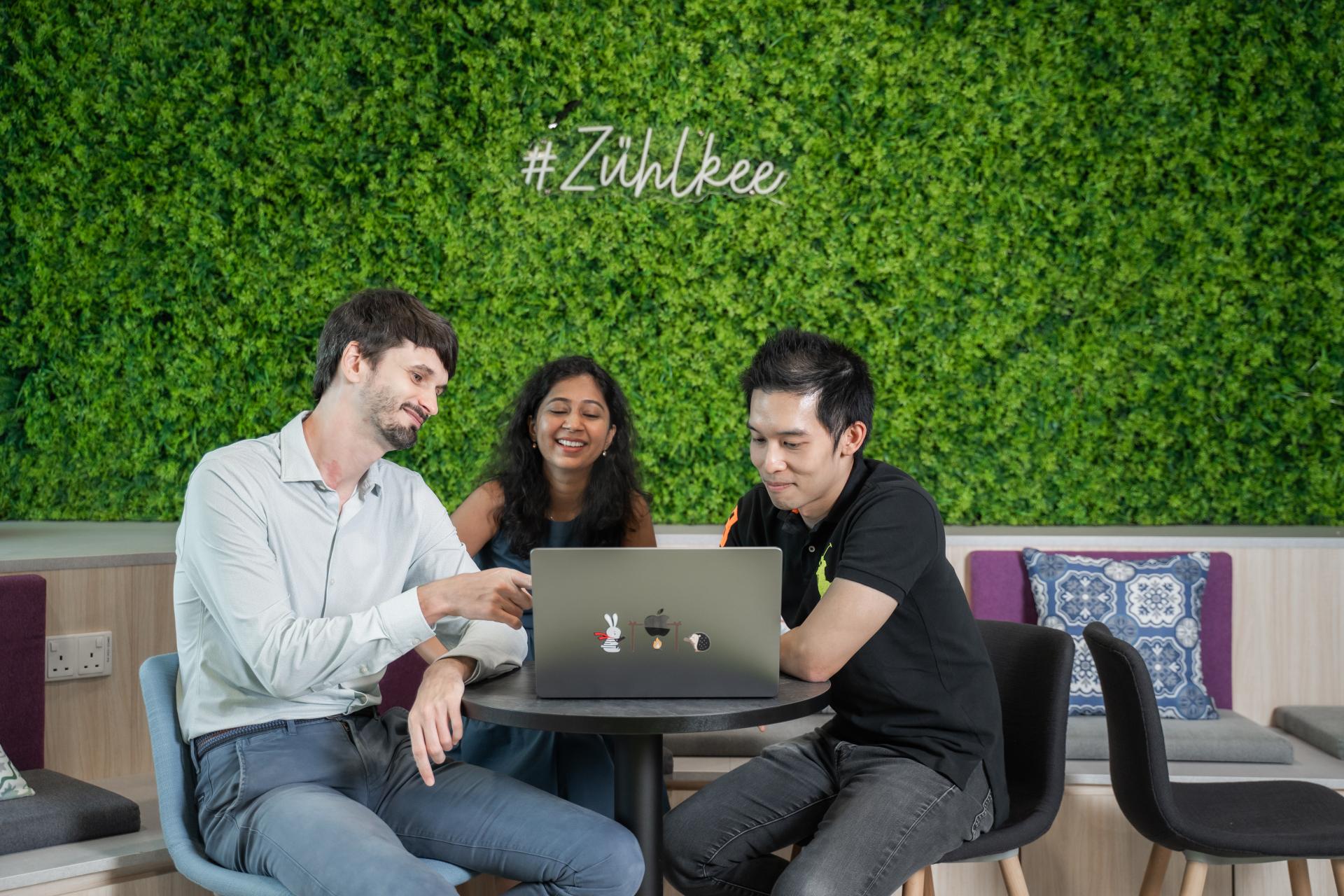 A group of colleagues. sitting at the office round table and smiling at the screen laptop you're looking at.