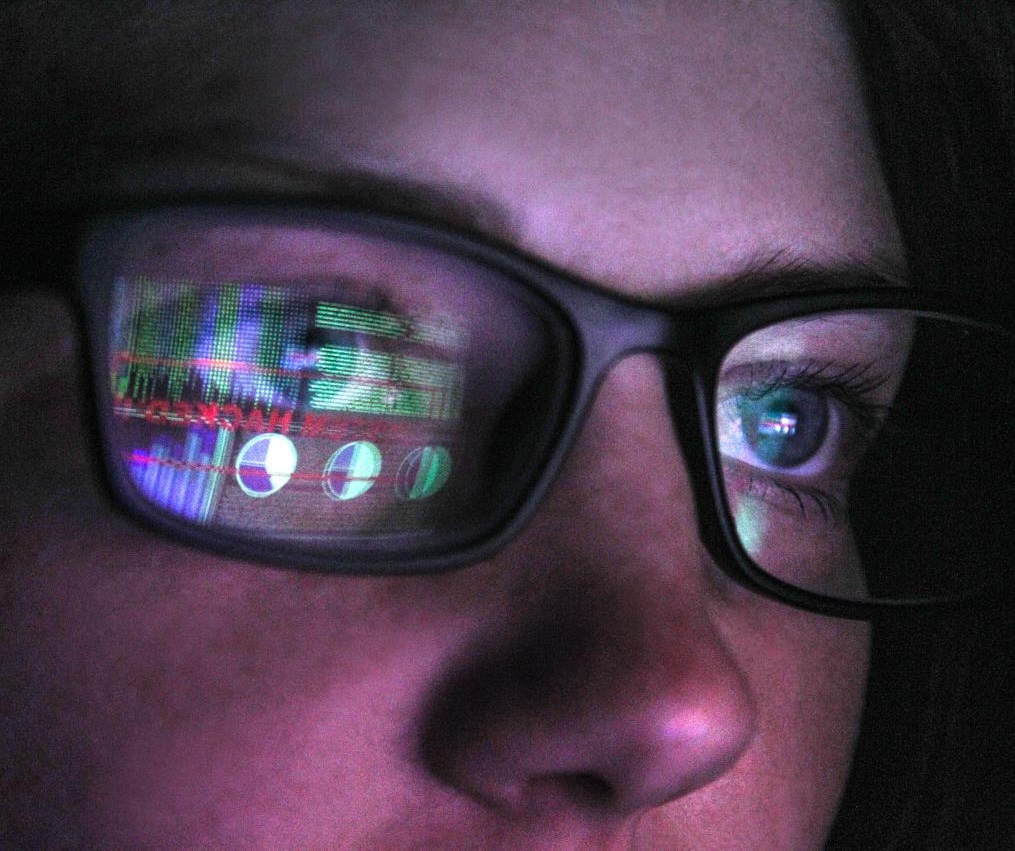 Person wearing glasses with a computer screen reflected in the lenses