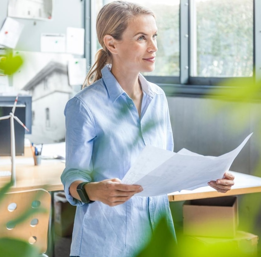 Woman in office working on plan with wind turbine model on table