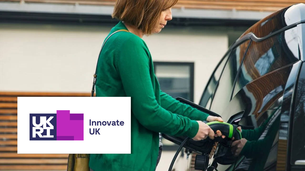 A woman plugging an electric vehicle charging cable into a car with Innovate UK logo