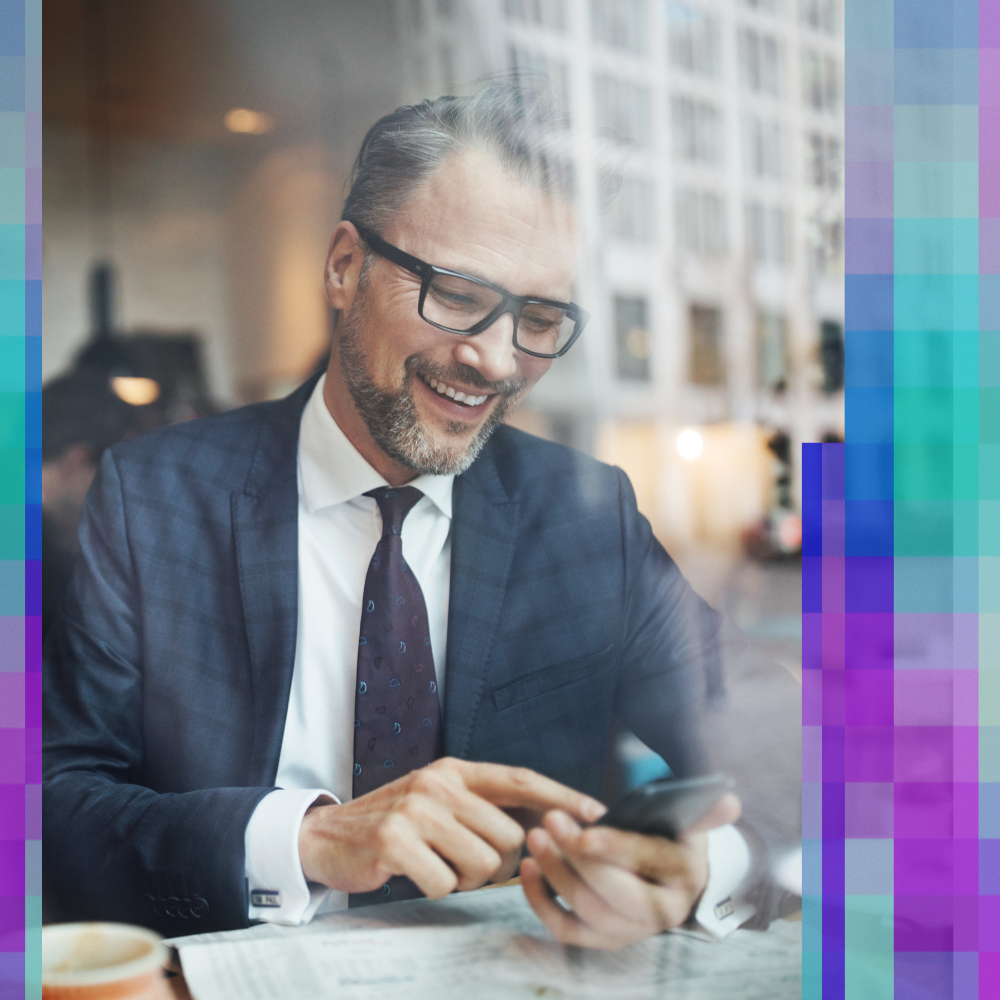 Man touching a phone while laughing in a coffee house